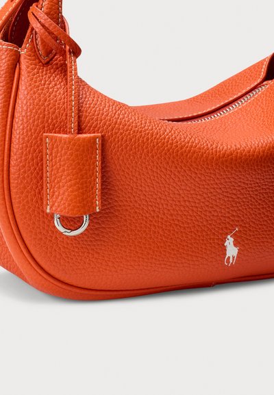 Usnjena torbica za ramo v živo oranžni barvi, z raznoliko teksturo, srebrnimi okraski in izrazitim logotipom na strani.