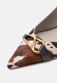 Καφέ και λευκό παπούτσι από δέρμα αγελάδας με μυτερή μύτη, μαύρο δερμάτινο λουρί και χρυσή πόρπη AllSaints.