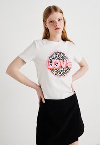 Bílý bavlněný tričko s kulatým potiskem s leopardím vzorem a růžovým nápisem "LOVE". Krátké rukávy a volný střih.