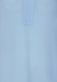 Tessuto blu chiaro con superficie texturizzata e righe verticali, completato da un dettaglio con scollatura rettangolare.