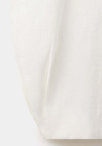Gros plan d'un tissu blanc avec une texture tissée diagonale visible et un pli doux au centre.