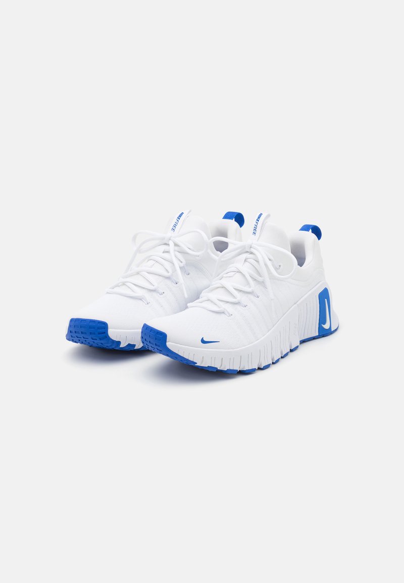 Zapatillas deportivas blancas con una parte superior de malla texturizada, acentos azules en el talón y la suela, cordones planos y un diseño de suela flexible.