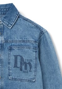 Giubbotto di jeans azzurro chiaro con colletto, tasca frontale con testo grafico di colore blu scuro e dettagli di cucitura visibili.