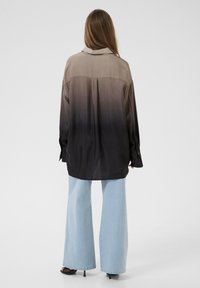 Langærmet skjorte i gradient nuancer fra beige til sort, lavet af glat stof, med klassisk krave og knappede manchetter, stylet med vide bukser.