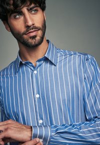 Blau gestreiftes Hemd mit weißen Streifen, ausgestattet mit klassischem Kragen und langen Ärmeln, zeigt eine glatte Stoffstruktur.