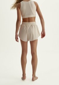 Beige atletisk crop top och matchande shorts, tillverkade av mjukt material, med en figurnära design, elastisk midja och en bakpanel.