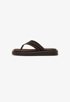 Sandalia tipo chancla de plataforma marrón con tachuelas doradas en la tira ancha y suela acolchada, presentada sobre un fondo blanco.