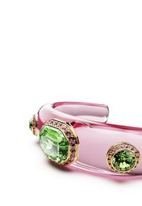 Pink acrylic bracelet featuring large green gemstones with gold accents, surrounded by smaller pink stones, showcasing an octagonal shape.