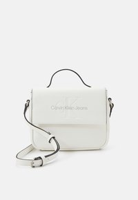 Bolso bandolera rectangular blanco con logo "CK" en relieve, correa ajustable y acentos negros. Textura suave y diseño minimalista.