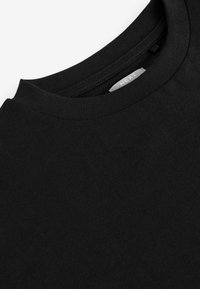 T-shirt en coton noir avec un col rond classique. Le tissu est lisse avec un léger peu d'élasticité, mettant en avant un design simple et minimaliste.