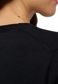 Schwarzer Strickpullover mit rundem Ausschnitt und gerippten Bündchen, mit einer strukturierten Oberfläche und sichtbaren Nähten entlang der Schulternaht.