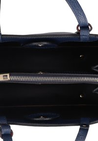 Interno di una borsa a mano in pelle blu con texture, cerniera argentata, fodera nera e due maniglie. Presenta accessori in metallo e tasche.