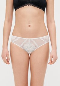 Weiße Spitze Slip mit transparenten Mesh-Einsätzen, floralem Muster auf der Vorderseite, elastischem Bund und glatter Oberfläche.