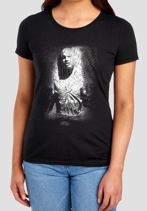 Frau trägt ein schwarzes T-Shirt mit einer monochromen Grafik von Han Solo, eingefroren in Karbonit aus Star Wars, und einem kleinen Star Wars-Logo darunter.