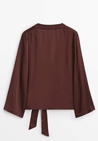 Ruskea, kevyt blouse pitkillä hihoilla, suoran leikkauksen ja nauhakiinnityksellä takana. Sujuva rakenne ja yksinkertainen muotoilu.