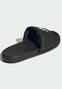 Black slide sandals with a textured strap, featuring a perforated design and contrasting white logo. Thick rubber sole for comfort.