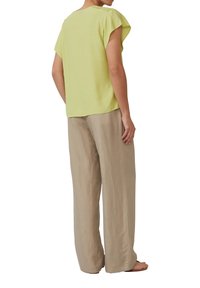 Lichtgroen t-shirt met korte mouwen en een comfortabele pasvorm, gecombineerd met beige wijde broekspijpen. De stof lijkt zacht met een gladde textuur.
