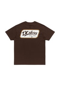 Brown cotton t-shirt featuring a large white and gold DC Shoes logo on the back. Short sleeves and a crew neck design.