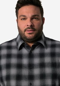 Camicia a quadri grigia e nera con design a bottoni, dotata di colletto, taschino sul petto e tessuto morbido e testurizzato.