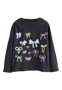 Črna majica z dolgimi rokavi z različnimi pisanimi pentljami iz bleščic v različnih velikostih in oblikah na sprednji strani.