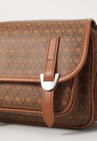 Borsa a fantasia marrone con una forma strutturata, dettagli in pelle liscia e una chiusura in metallo argentato. Presenta una finitura testurizzata e cuciture in evidenza.