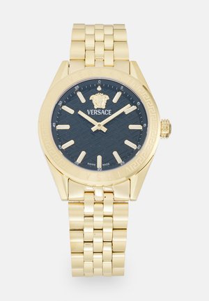 Gold-tone wristwatch with a navy textured dial, gold hands, and a lion emblem. Features a metal bracelet and engraved bezel detailing.