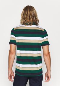 Grön och marinrandig polo skjorta med vita och beige accenter; korta ärmar, ribbat krage och rak fåll. Slät bomullstyg.