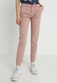 Světle růžové bavlněné chinos kalhoty se střihem do rovna, s poutky na pásek, předním zapínáním na knoflík a bočními kapsami. Kombinováno s bílými teniskami.