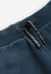 Heren donkerblauwe joggers met een geribbelde tailleband, voorzien van zwarte trekkoordaccenten en logodetails op de tailleband. Van een katoenen mixmateriaal.