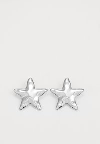 Orecchini a forma di stella argentata con superficie lucida e lucente. Ogni orecchino presenta cinque punte e sottili dettagli di texture sulla superficie.