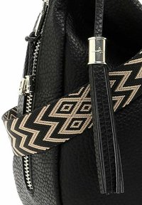 Sac en cuir noir texturé avec une fermeture éclair et des accessoires en argent, doté d'une bandoulière amovible noire et beige à motif géométrique.