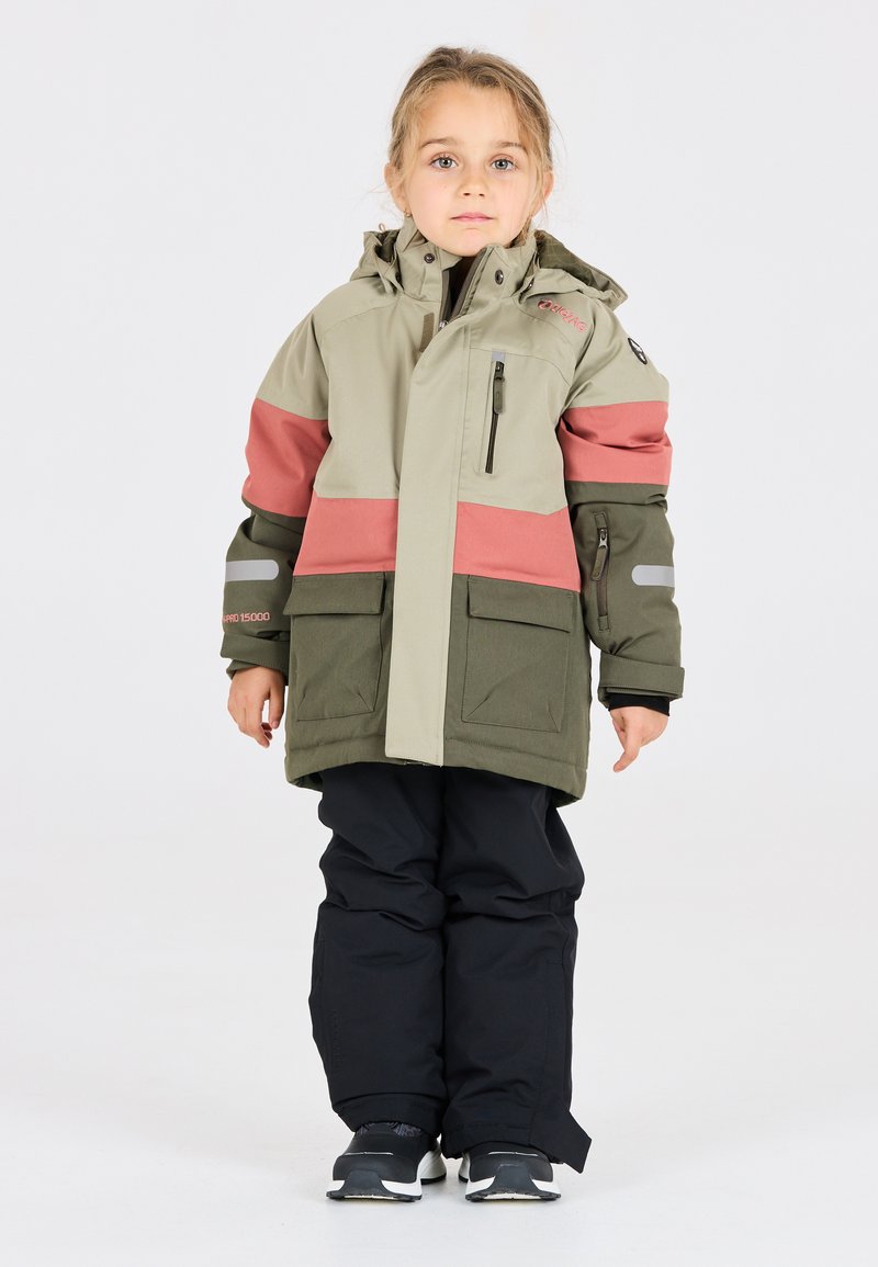 Chaqueta de exterior para niño en verde claro y coral, con bolsillos grandes, capucha ajustable y detalles reflectantes; combinada con pantalones de nieve negros.