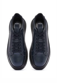 Zapatillas de piel azul marino con cordones planos, punta redonda y laterales texturizados. Presentan una suela de goma negra y un diseño minimalista.