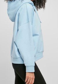 Ljusblå hoodie med avslappnad passform, dragsko i huvan och frontficka. Ribbad mudd vid ärmar och nederkant. Mjuk bomullsblandning.