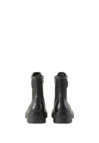 Bottines noires avec une finition en cuir lisse, des panneaux élastiques sur les côtés et une semelle épaisse, présentant des accents de logo sur le talon et le côté.