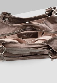 Brązowa skórzana torebka z otwartą główną komorą, ukazująca jasne wykończenie wnętrza, wewnętrzną kieszeń na zamek oraz oddzielne sekcje.