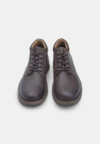 Scarpe in pelle marrone con lacci e punta arrotondata, caratterizzate da cuciture a contrasto, un colletto imbottito e suole in gomma testurizzata.