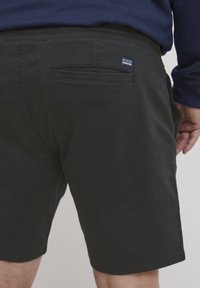 Pantalones cortos de algodón negros con un bolsillo trasero, con una pequeña etiqueta azul "BLEND". Cierre con una cinturilla lisa y corte recto.