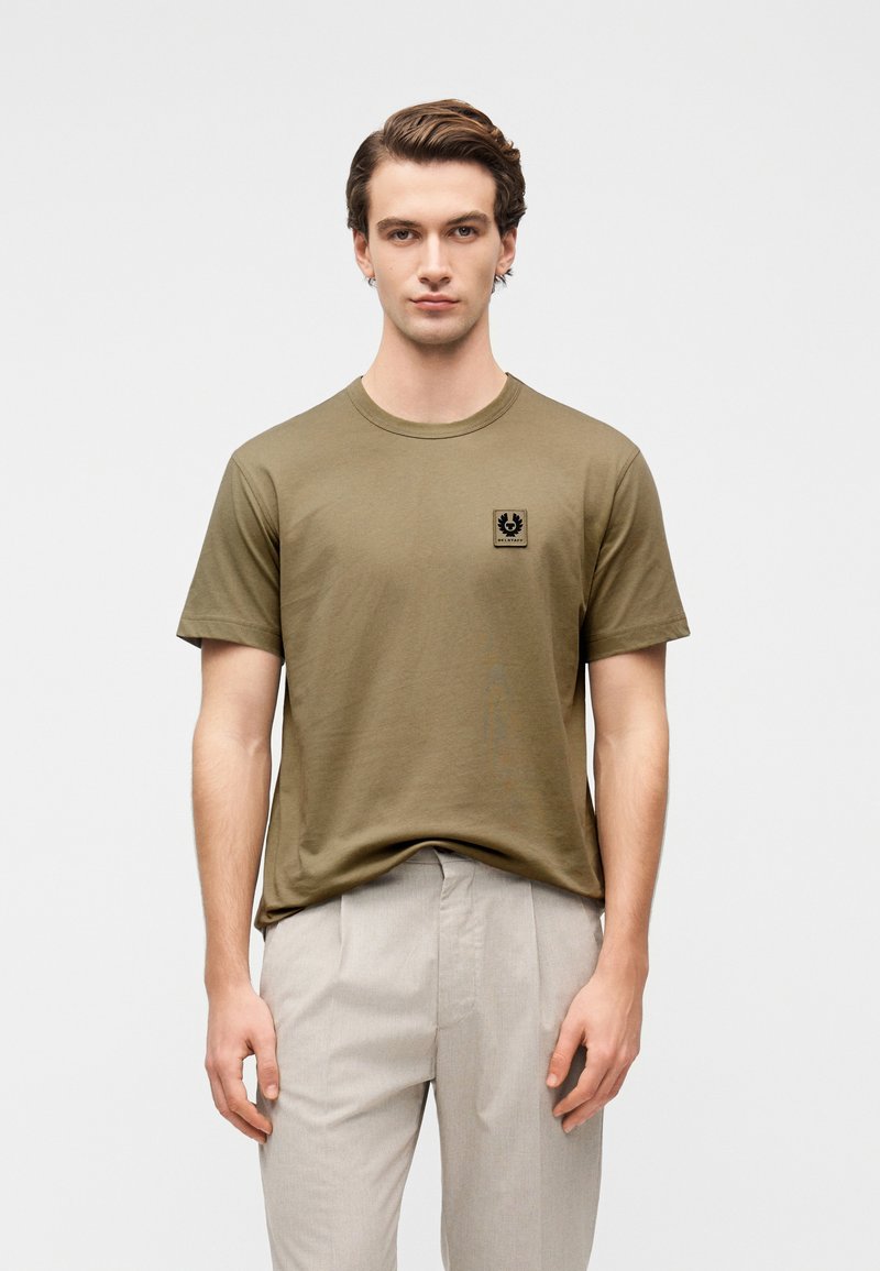 Λαδί βαμβακερό t-shirt με κοντά μανίκια και στρογγυλή λαιμού, με μικρό μαύρο εμβληματικό κέντημα στο αριστερό μέρος του στήθους.