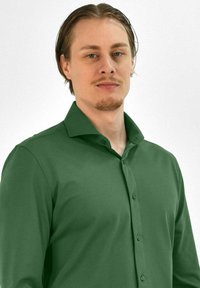 Groene langemouwen shirt van soepel materiaal, met een kraag en verschillende knopen aan de voorkant. Sluit nauw aan op het torso met rechte mouwen.