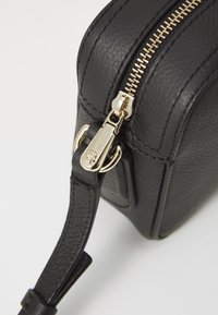 Borsa in pelle nera con forma strutturata, superficie texturizzata, hardware in oro per la zip e attacco per la tracolla in pelle.