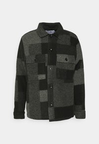 Chaqueta de lana gris oscuro y negra a cuadros con cierre delantero de botones y dos bolsillos delanteros con solapa y botones, mangas largas y cuello.