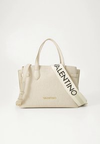 Beige läderhandväska med präglad logotyp, två överhandtag och en avtagbar rem med varumärkesnamnet i svart. Guldiga metallaccenter.