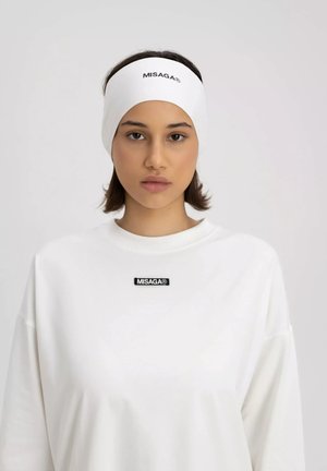 Witte stoffen haarband met zwart "MISAGA®" logo; gecombineerd met een losvallende witte sweatshirt met een soortgelijk zwart logo patch.