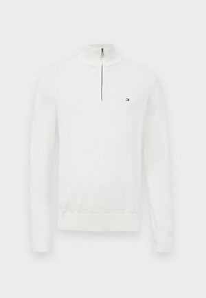 Fehér, hosszú ujjú pulóver negyed cipzárral és kis téglalap alakú logóval a bal mellen, sima háttéren bemutatva.