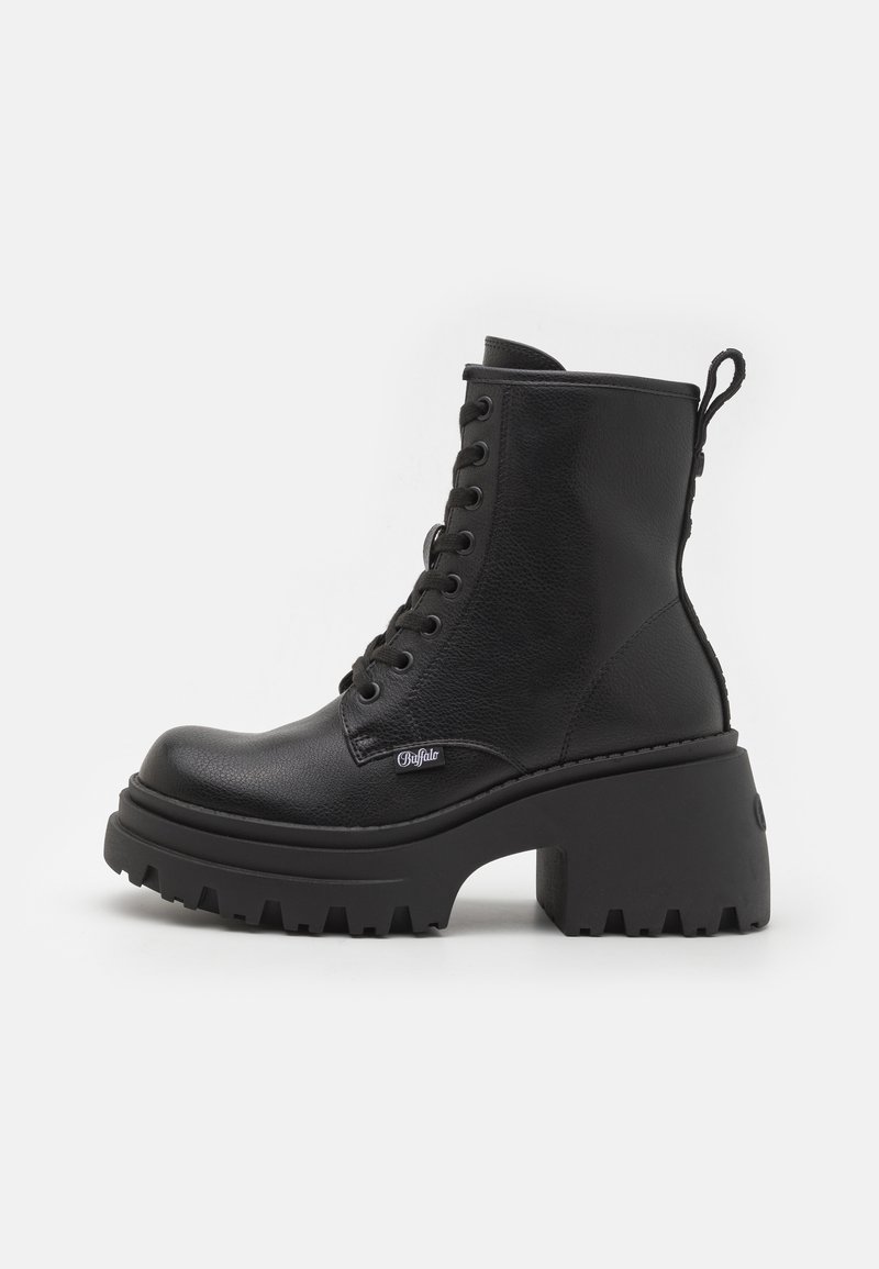 Bottine noire en cuir à lacets avec talon épais bloc, semelle à crampons et languette de tirage à l'arrière, vue de profil sur fond blanc.