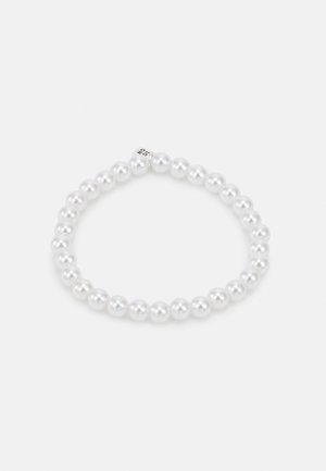 Elastisk armbånd laget av ensartede hvite perler, med en glatt, blank finish. Et diskret design med en sikker lukking i sølvperle.