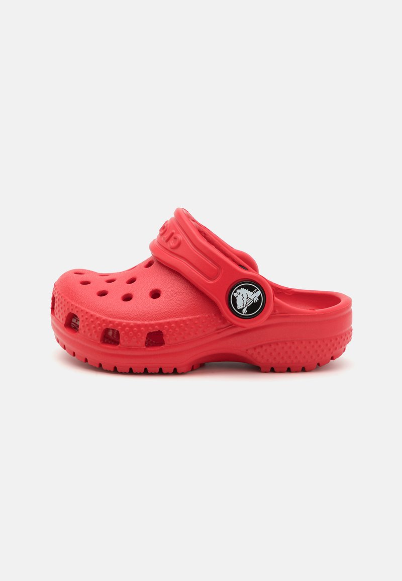 Red plastic clog with ventilation holes, a back strap, and textured soles. Features a circular logo accent on the side.