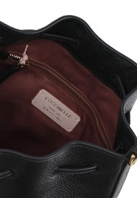 Borsa a secchiello in pelle nera con esterno texturizzato, interno in tessuto borgogna a contrasto e una tasca con zip dorata. Presenta un'etichetta del marchio all'interno.