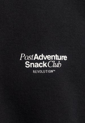 Zwarte stof met ribbelstructuur met witte geborduurde tekst: "Post Adventure Snack Club REVOLUTION™." Eenvoudig en modern ontwerp.